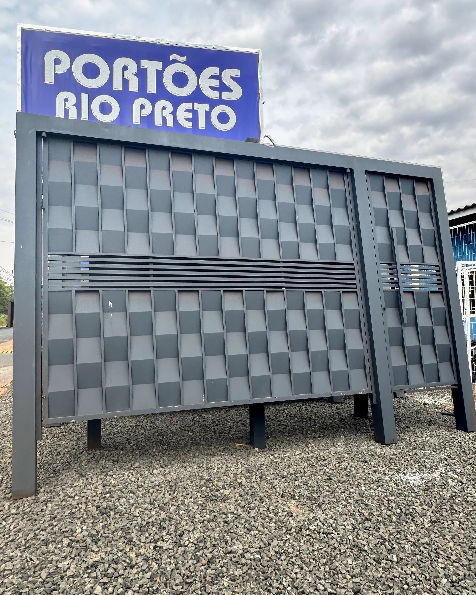 Portão com desenho xadrez em relevo exposto sob o letreiro da Portões Rio Preto